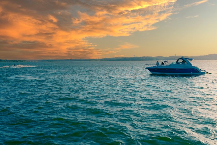 A boat on calm water under a dramatic orange sky at sunset.